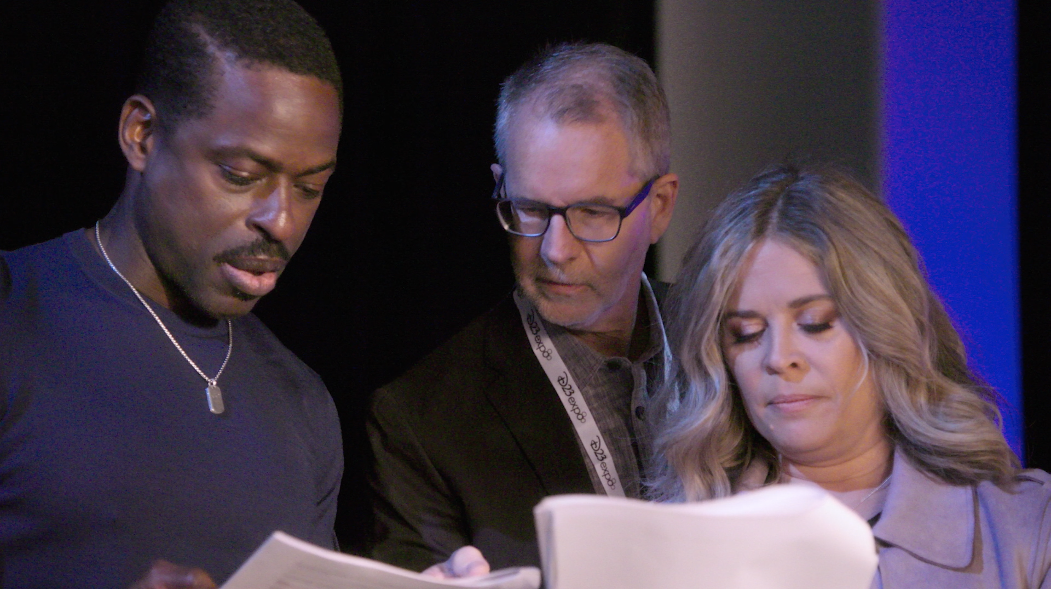 Jen and two men reading documents.