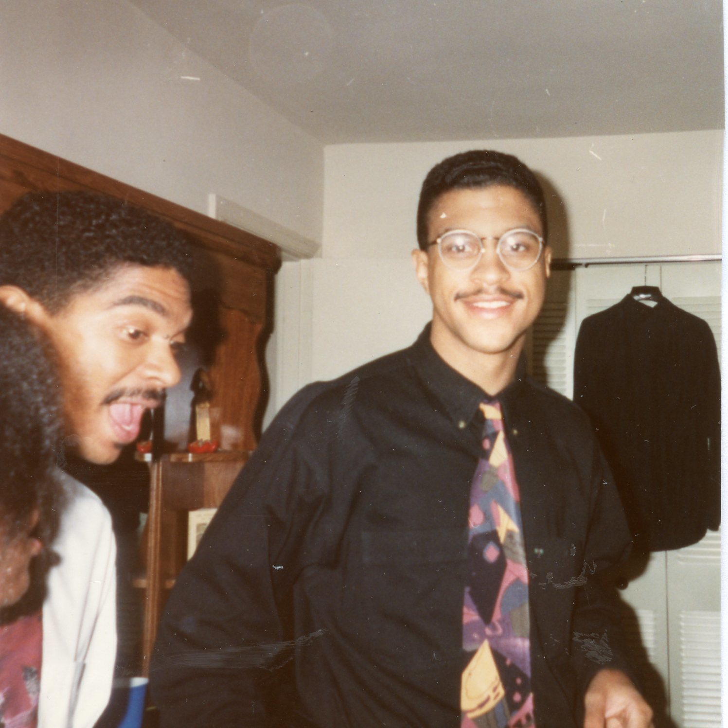 Stan as a young man smiling at the camera and another man.