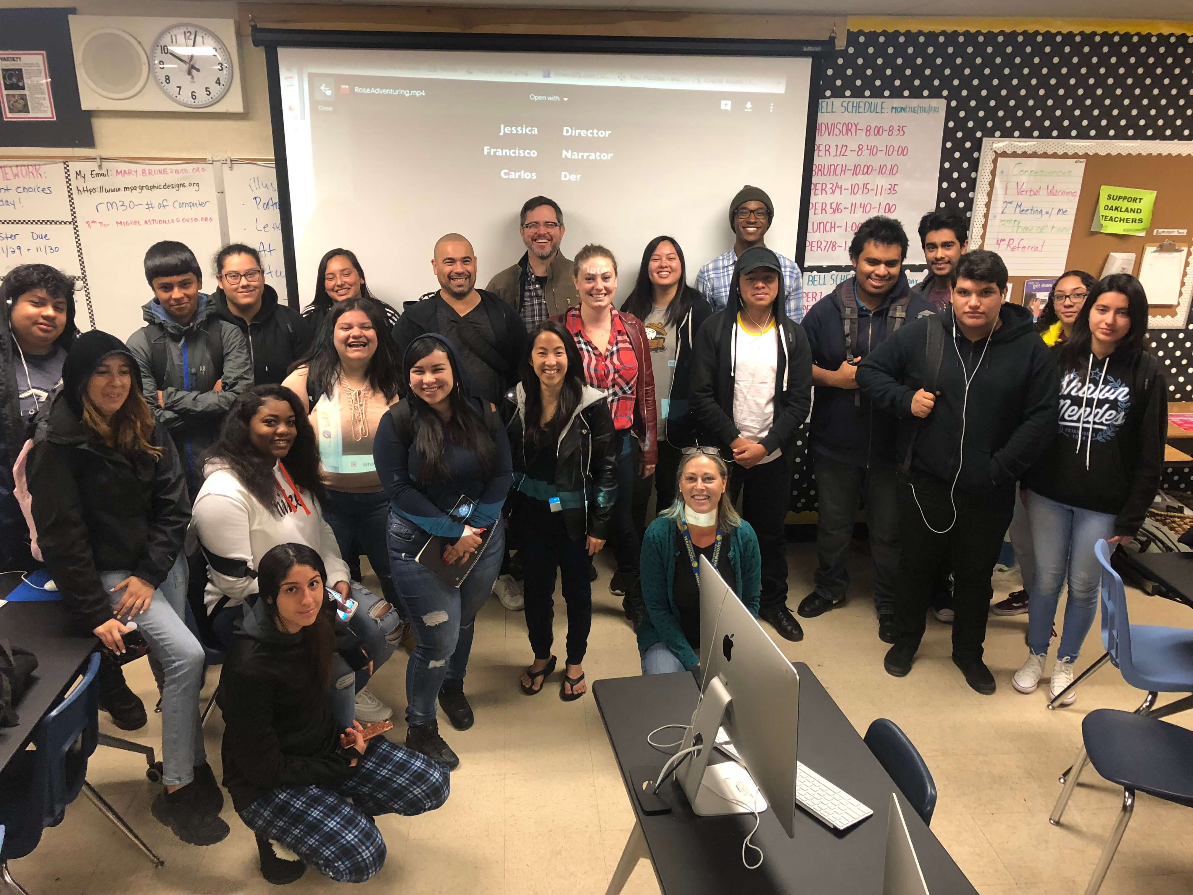 A group photo of several people in front of a projector screen.
