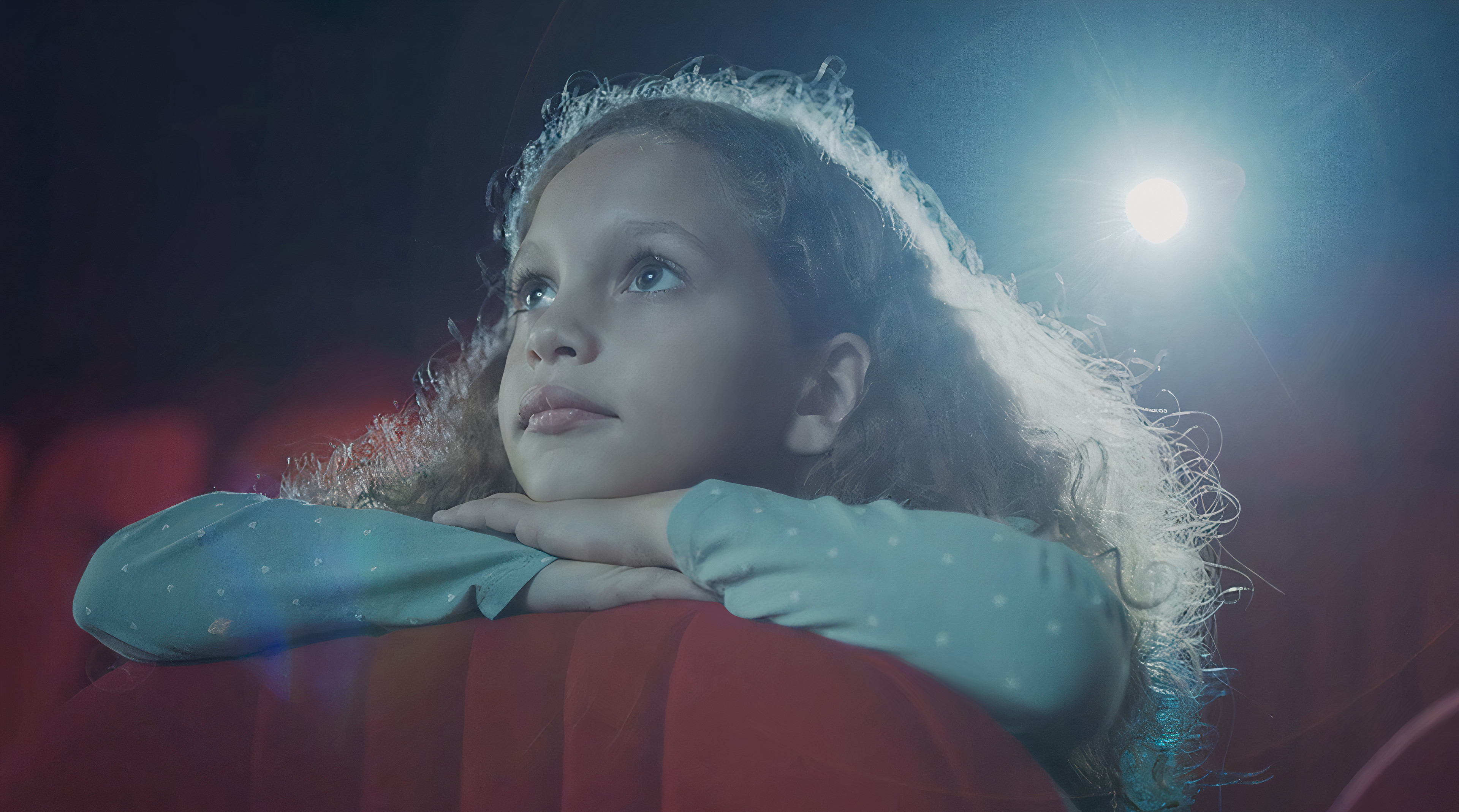 A young girl sitting in a movie theatre